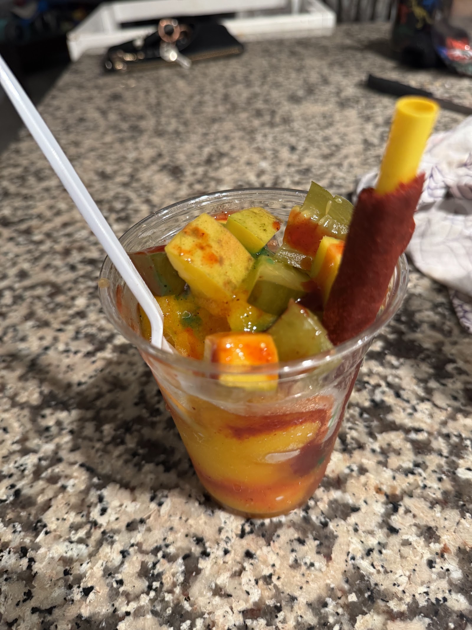 Mangonada fruit cup with chamoy and a tajin-rimmed straw